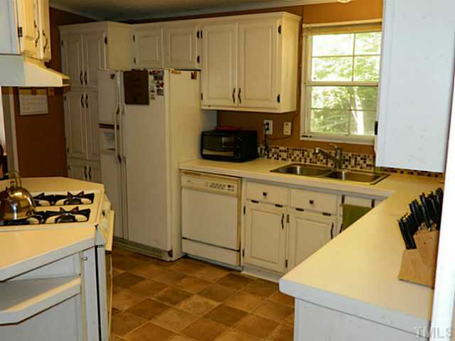 2028 Carpenter Pond Road Raleigh, NC 27613 - Photo 12 of 23 a kitchen with white cabinets and appliances