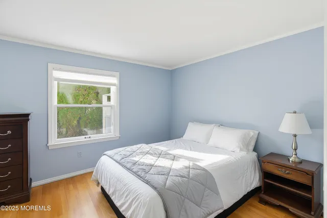 a spacious bedroom with a bed a dresser and a flat screen tv