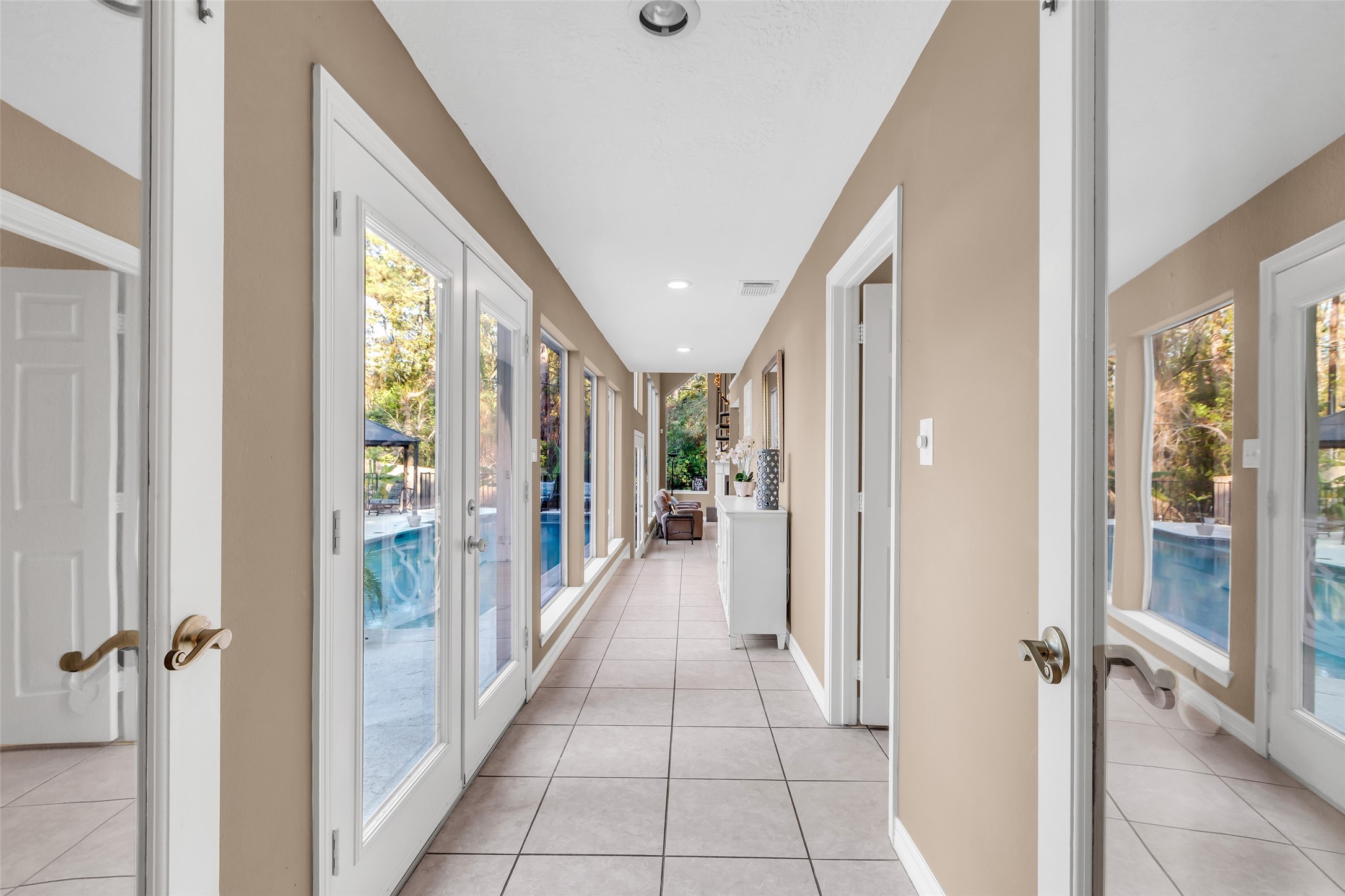24102 Northcrest Drive Spring, TX 77389 - Photo 19 of 31 This sunlit hallway, with expansive windows showcasing pool views, seamlessly guides you into the inviting second family area, perfect for relaxation and gatherings.