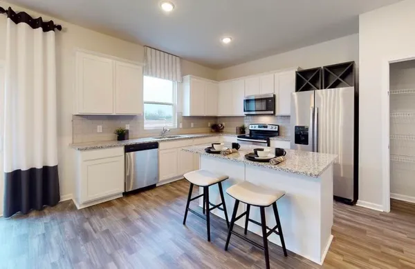 a kitchen with a refrigerator a stove a sink dishwasher and a microwave with wooden floor