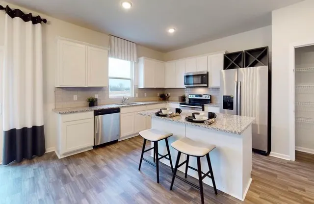 a kitchen with a refrigerator a stove a sink dishwasher and a microwave with wooden floor