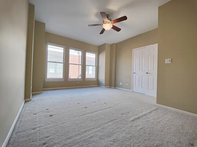 an empty room with windows and fan