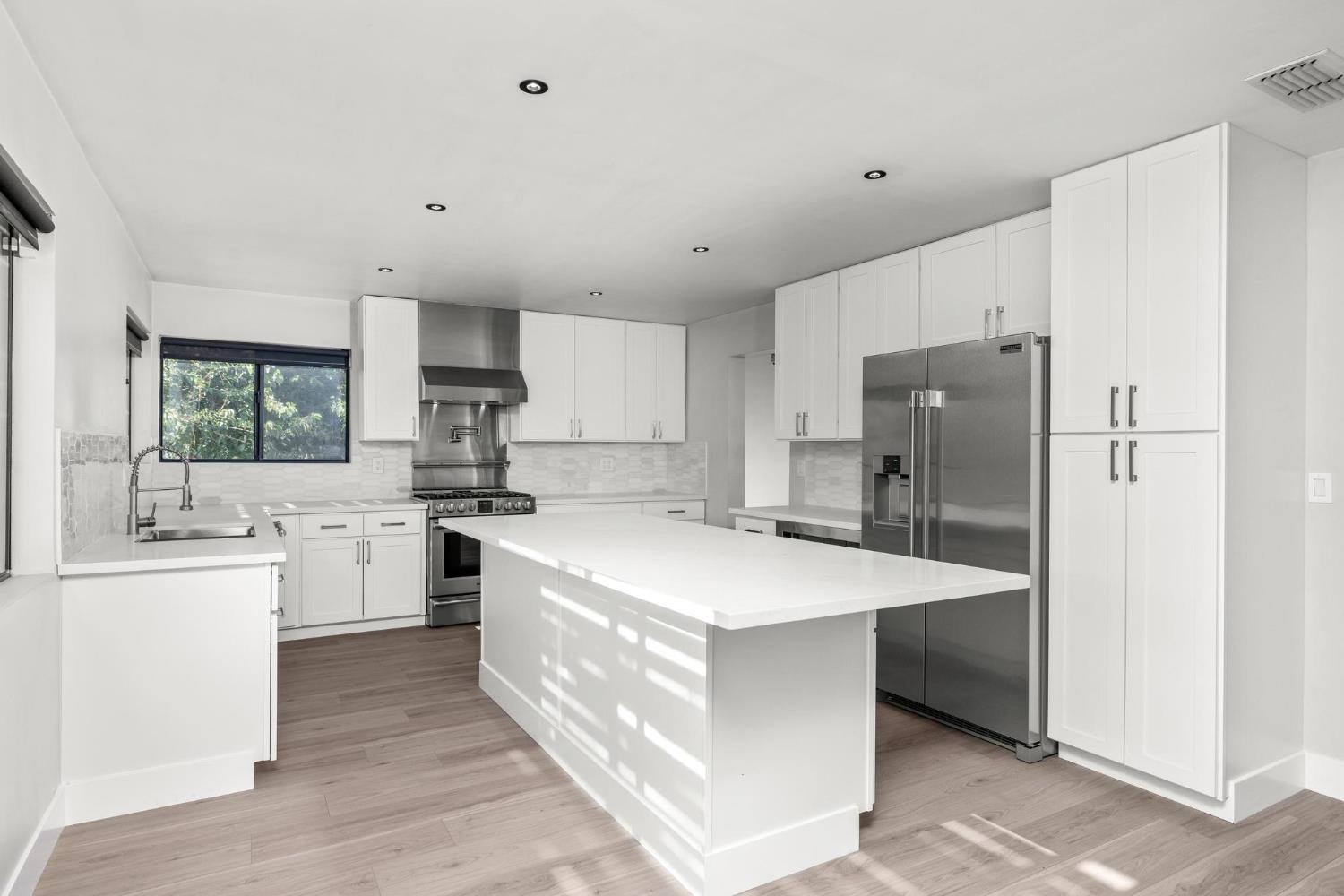 29879 South Chrisman Road Tracy, CA 95304 - Photo 13 of 50 a large kitchen with stainless steel appliances a refrigerator a sink dishwasher a stove with white cabinets and wooden floor