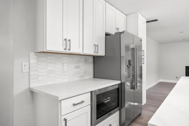 a bathroom with a granite countertop sink a large mirror a bathtub and next to a window