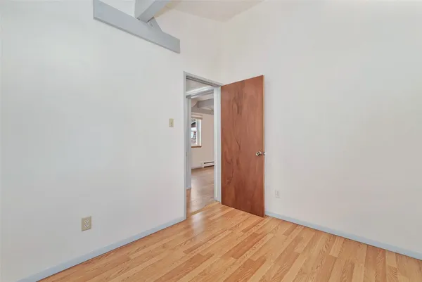 a view of an empty room with wooden floor and closet
