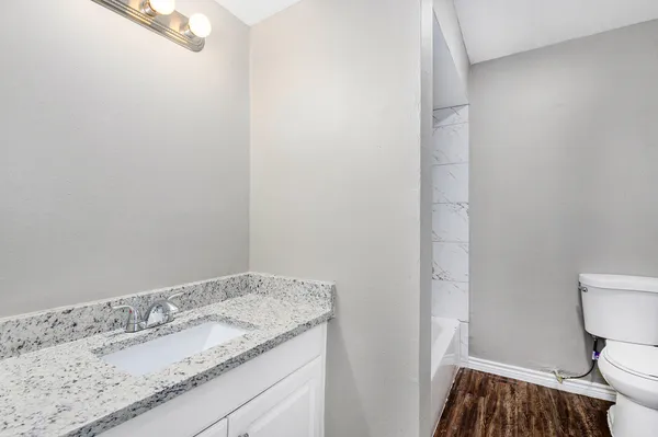 a bathroom with a granite countertop sink and a toilet