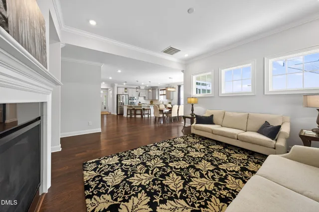 a kitchen with stainless steel appliances granite countertop a kitchen island a stove a refrigerator a sink a dining table and chairs with wooden floor