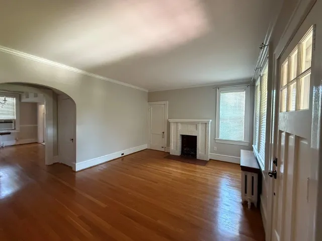 an empty room with wooden floor fireplace and windows