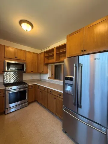 a kitchen with stainless steel appliances granite countertop a refrigerator a stove and a sink