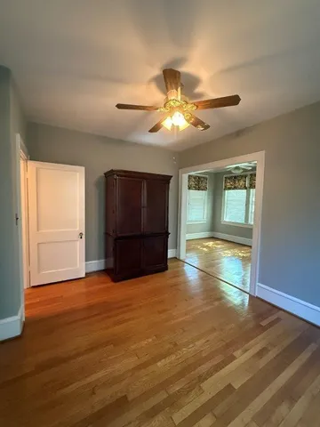 a view of an empty room with a window and wooden floor