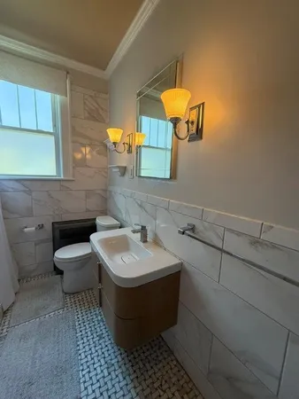 a view of a hallway with wooden floor and a bathroom