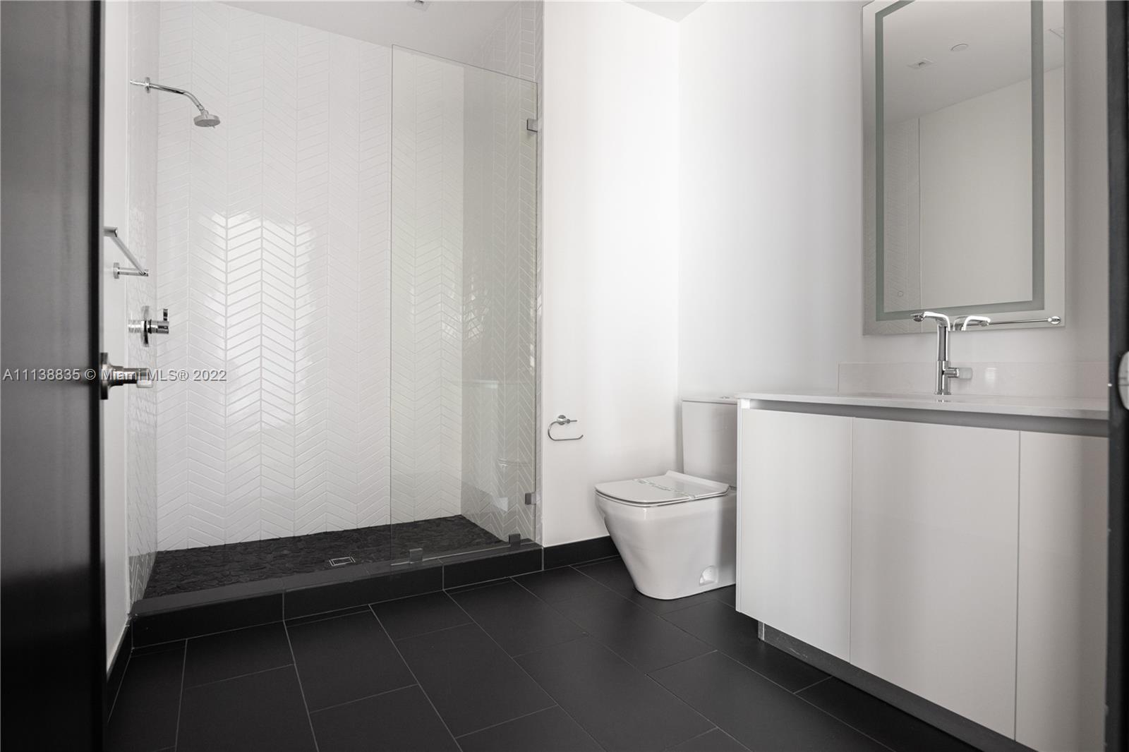 340 Southeast 3rd Street, Unit PH4 Miami, FL 33131 - Photo 19 of 62 a bathroom with a sink a toilet and a mirror