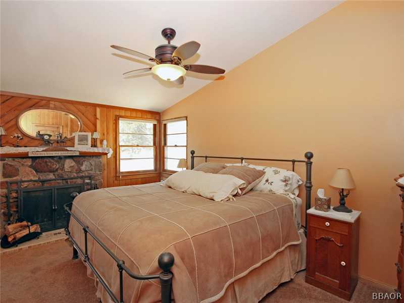 1004 Canyon Road Fawnskin, CA 92333 - Photo 12 of 25 a bedroom with a bed and a chandelier