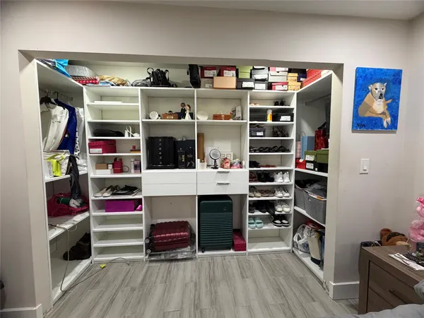 a view of walk in closet with clothes and shoes