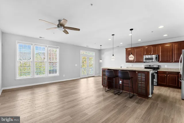 a living room with stainless steel appliances kitchen island hardwood floor and a window