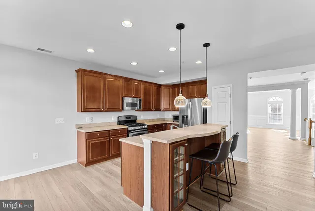 a kitchen with stainless steel appliances granite countertop a stove top oven a sink dishwasher a dining table and chairs with wooden floor