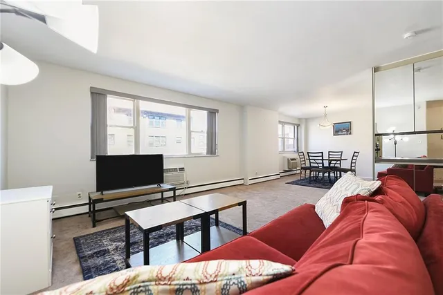 a living room with furniture a flat screen tv and a window
