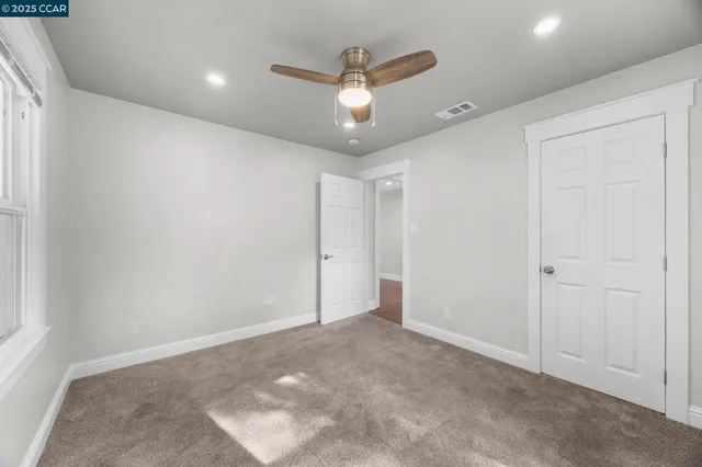en empty room with ceiling fan and window