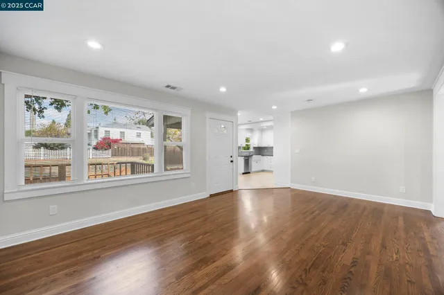 a view of empty room with wooden floor and window