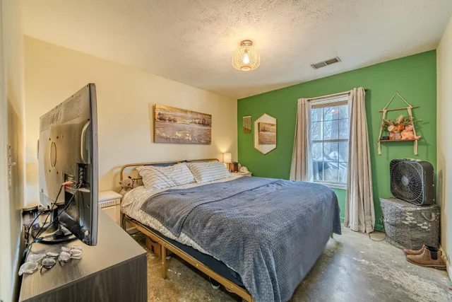 a bedroom with a bed and a flat tv screen on the dresser