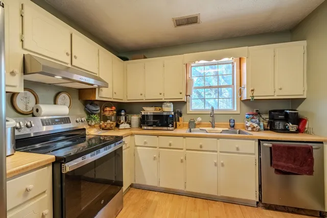 a kitchen with stainless steel appliances granite countertop a sink a stove and cabinets