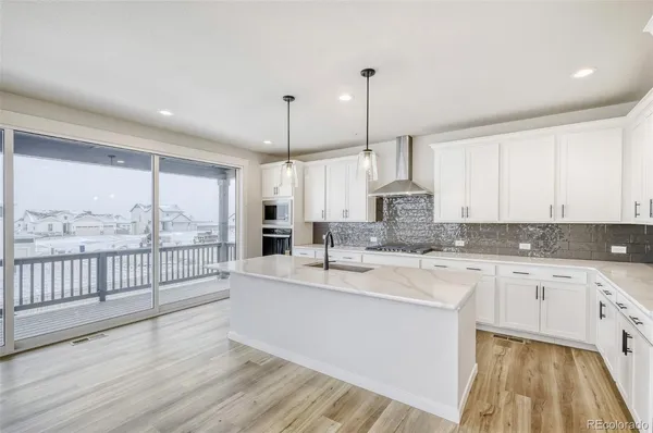 a large kitchen with kitchen island a large window a sink stainless steel appliances and cabinets