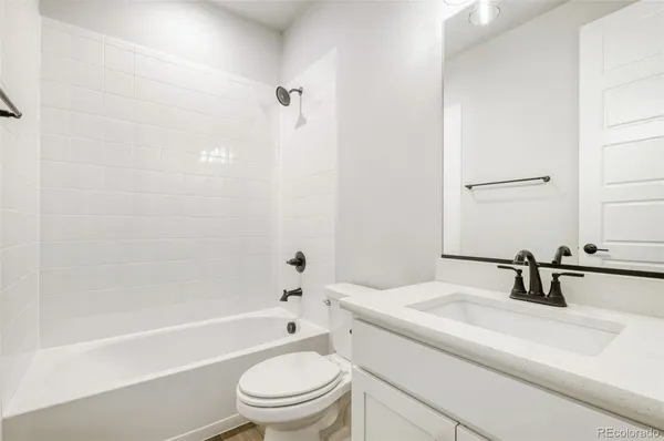 a bathroom with a bathtub shower sink vanity mirror and toilet