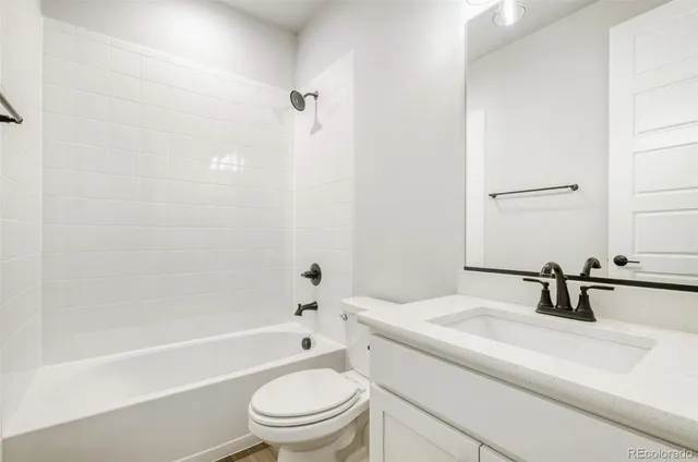 a bathroom with a bathtub shower sink vanity mirror and toilet