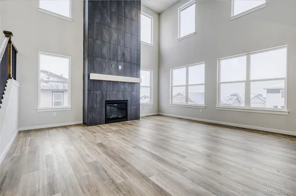 an empty room with wooden floor fireplace and windows