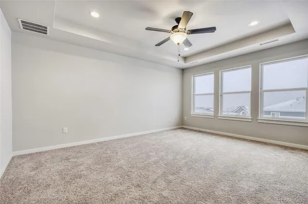 an empty room with a ceiling fan and windows
