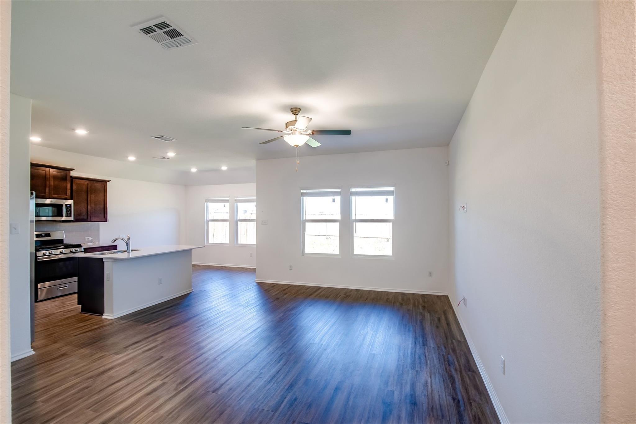 614 Milliner Loop Hutto, TX 78634 - Photo 24 of 25 An open-concept living area boasts lustrous wood flooring and a kitchen island, perfect for gathering.