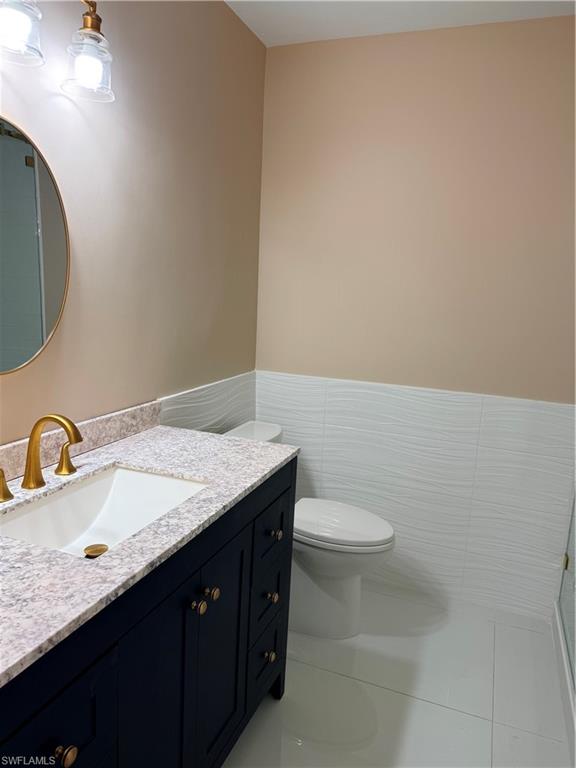 1575 Curlew Avenue, Unit 1 Naples, FL 34102 - Photo 28 of 35 Guest Bathroom with vanity, tile walls, light tile patterned flooring, and wainscoting