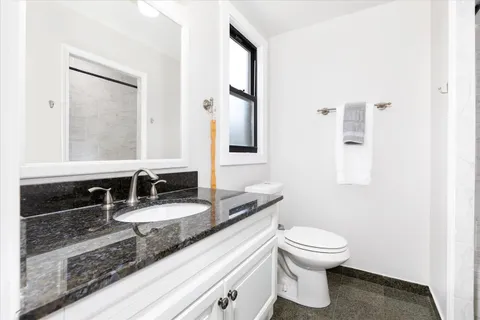 a bathroom with a granite countertop sink a mirror and a toilet