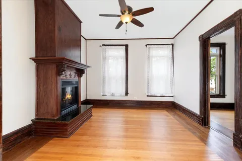 a view of an empty room with wooden floor and a fireplace