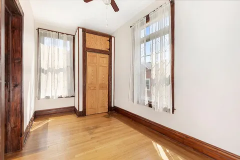 an empty room with wooden floor and sliding window