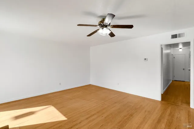 a view of a big room with wooden floor and windows
