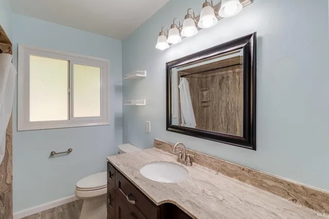 a bathroom with a granite countertop toilet sink and mirror