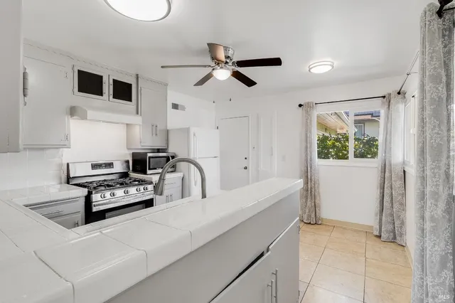 a kitchen with a refrigerator a stove a microwave and white cabinets