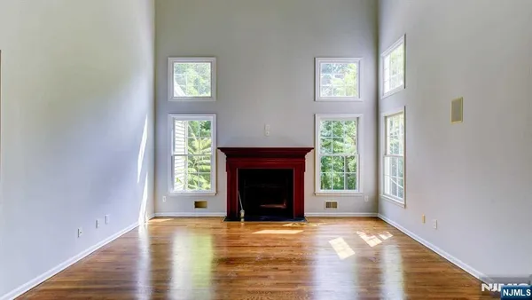 a view of an empty room with wooden floor fireplace and a window