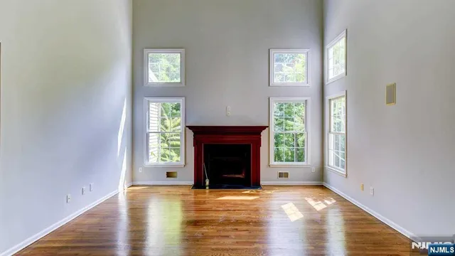 a view of an empty room with wooden floor fireplace and a window