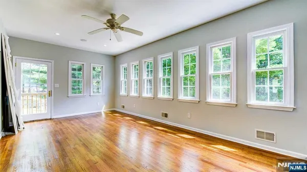 a view of an empty room with a window and wooden floor
