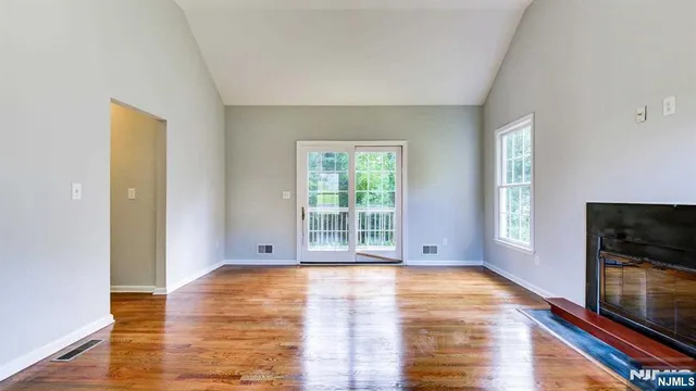 a view of empty room with wooden floor and fireplace