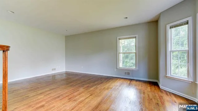 a view of an empty room with wooden floor and window