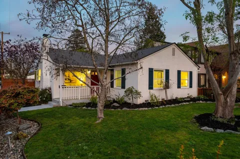 a front view of a house with a garden and trees