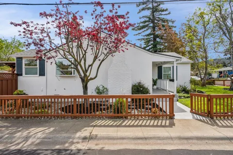 a view of a house with wooden deck and a bench