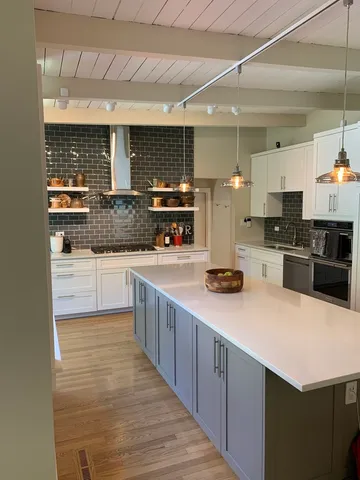 a kitchen with stainless steel appliances a sink counter space cabinets and a large window