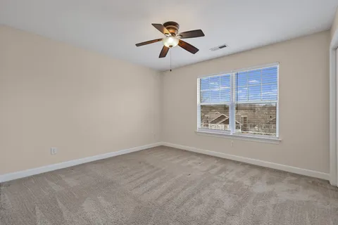 an empty room with ceiling fan and window