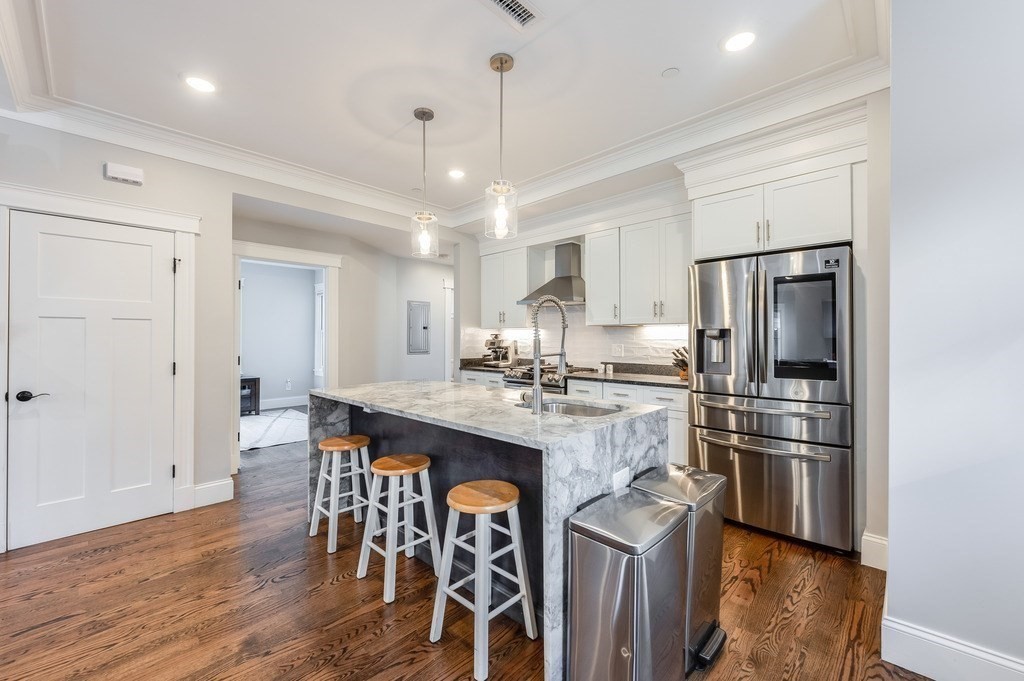 11 Preston Road, Unit 2 Somerville, MA 02143 - Photo 15 of 30 a kitchen with stainless steel appliances granite countertop a refrigerator a stove a sink dishwasher a dining table and chairs with wooden floor