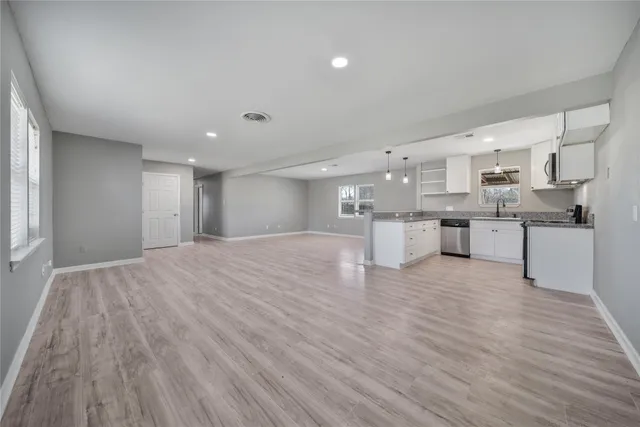 a large white kitchen with kitchen island a sink dishwasher a stove and a refrigerator with wooden floor