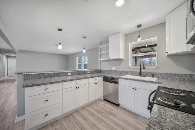 a kitchen with granite countertop white cabinets white appliances and a sink